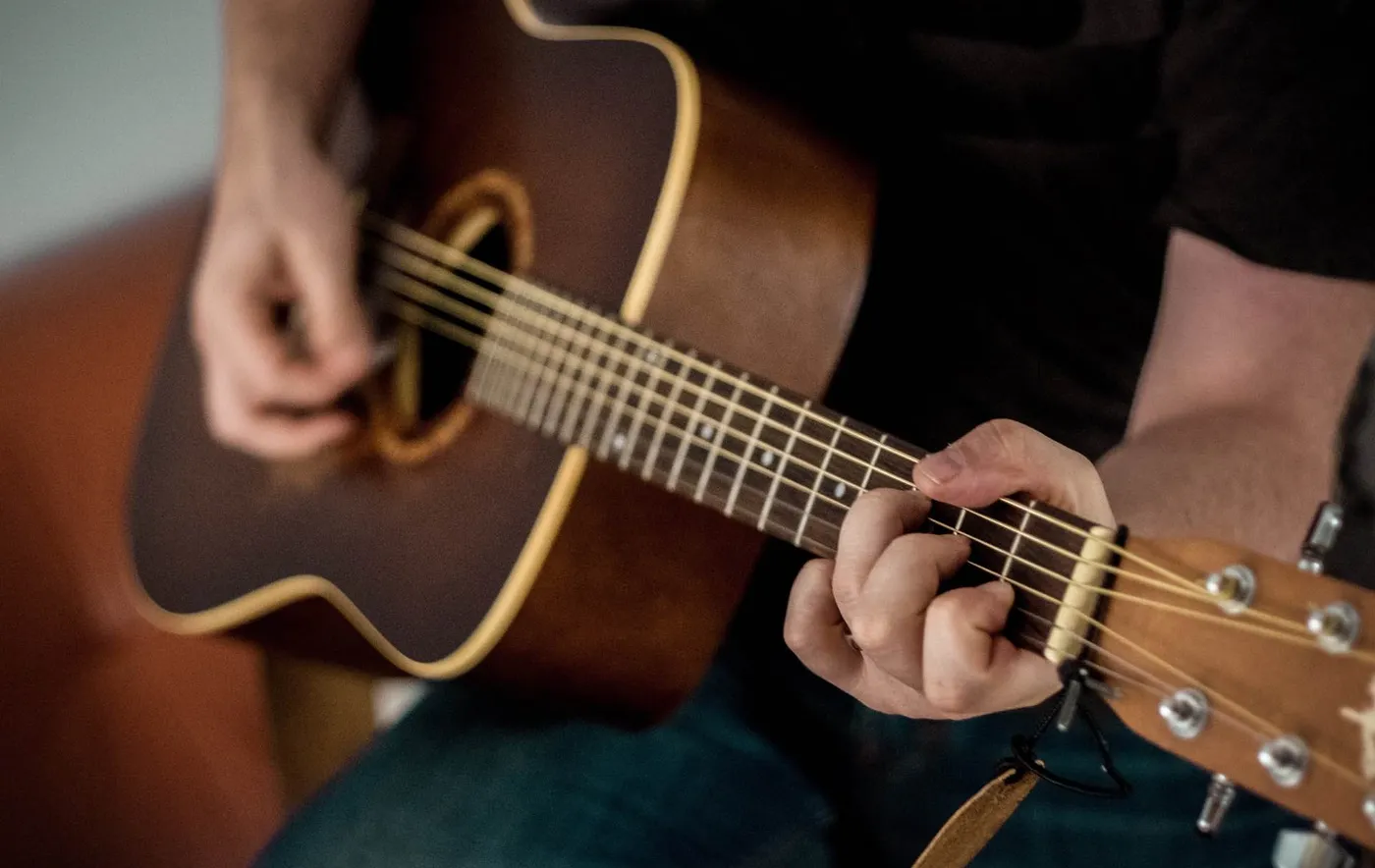 Hands playing an acoustic guitar